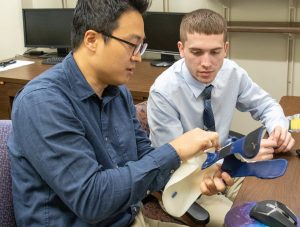 Hwan Choi and student examine a prosthetic