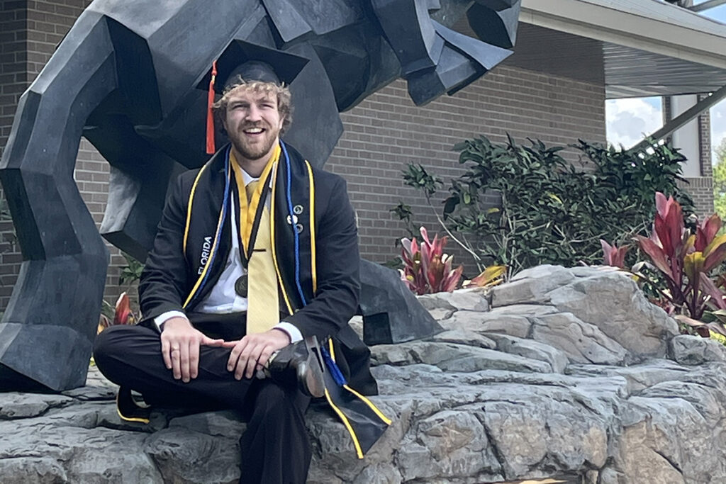 Zac Whitacre sits in front of the alumni center
