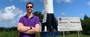 Brandon Kutchera stands in front of the Artemis rocket